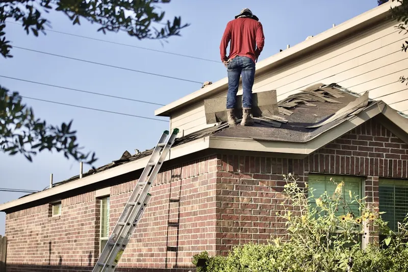 Professional roofer working on a residential roof in Alden